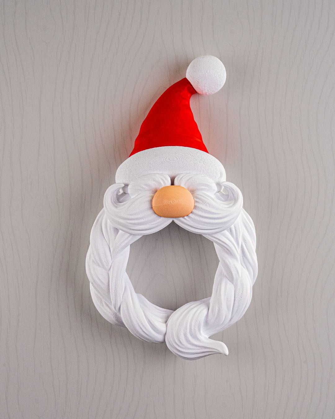 Weihnachtsmann Türkranz Santa's Welcome, Frontalansicht mit Bart-Kranz und roter Zipfelmütze vor heller Holzoptik-Wand, 33 cm – Münch3D