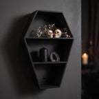 Coffin shelf with two skulls among dried flowers, a black candle and a purple amethyst crystal