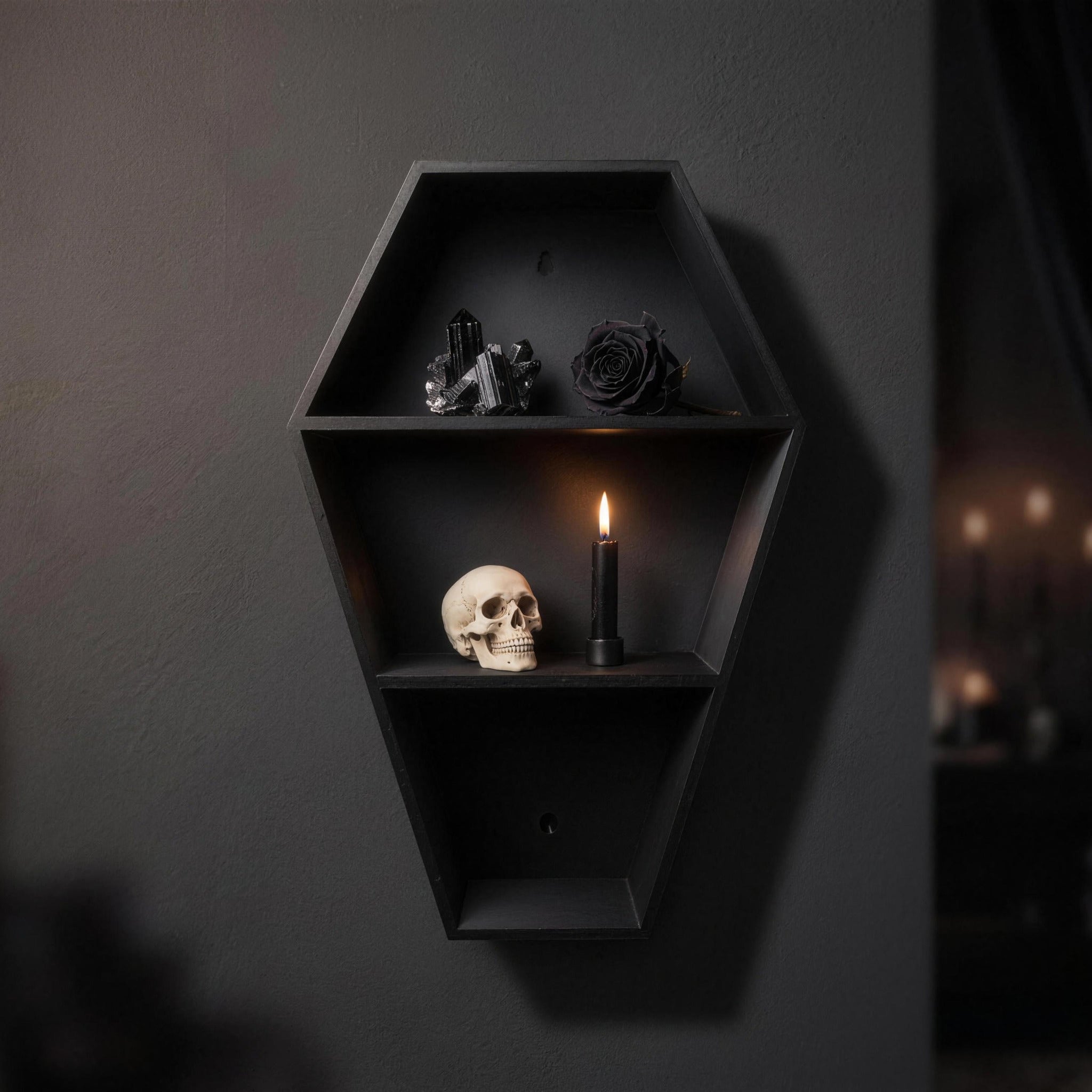Coffin shelf with a black crystal cluster, a black rose, a skull and a black vase with wilted roses