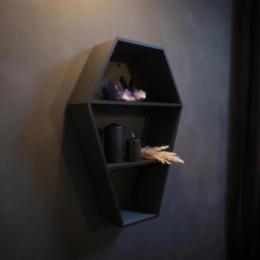 Coffin shelf photographed at an angle with an amethyst crystal, two black candles and dried grass decor