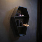 Coffin shelf photographed at an angle with an amethyst crystal, two black candles and dried grass decor