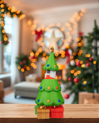 Pop-up-Weihnachtsbaum mit verstecktem Weihnachtsmann, Rückansicht schräg, auf Holzregal, weihnachtliche Girlande und Lichterkette im Hintergrund