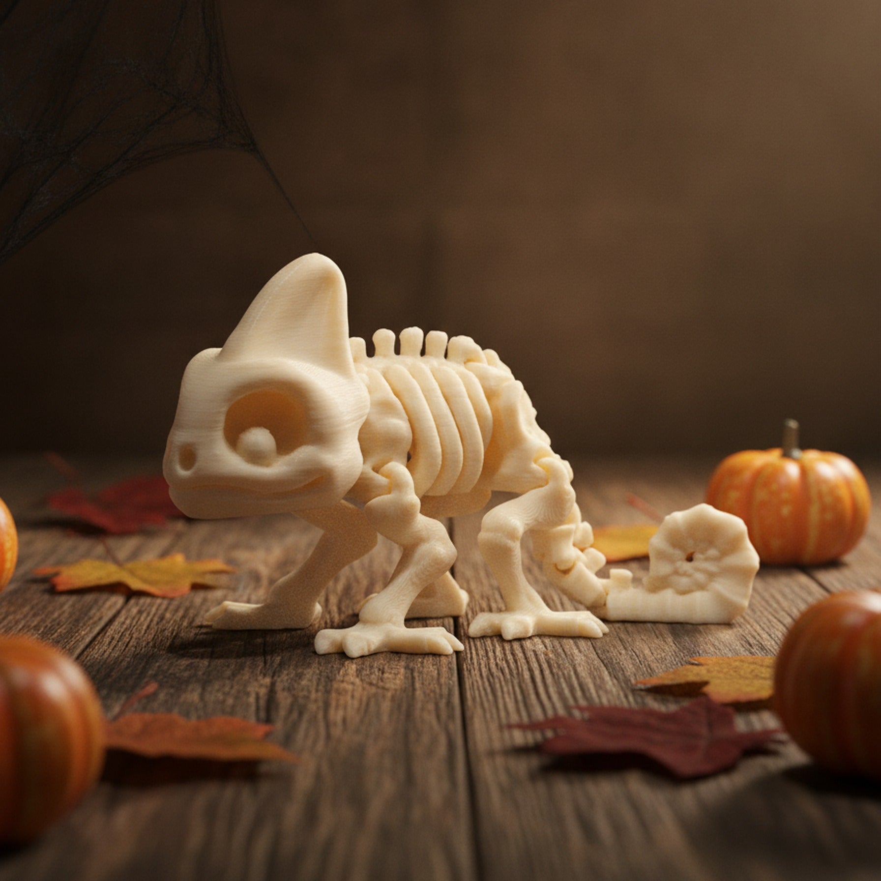 Skelett-Chamäleon-Figur aus leicht erhöhtem Dreiviertel-Blickwinkel auf Holzuntergrund, Helmkopf und eingerollter Schwanz gut sichtbar, mit Kürbissen und Herbstblättern als Halloween-Tischdeko