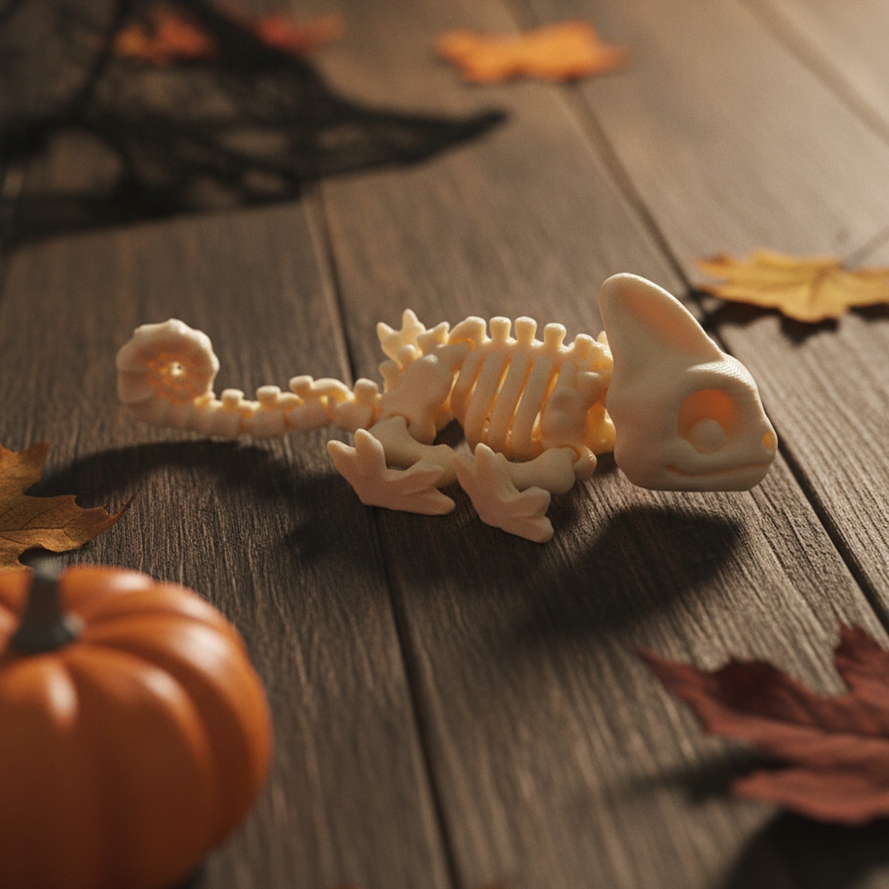 Skelett-Chamäleon-Figur in Detailaufnahme mit Fokus auf dem spiralig eingerollten Schwanz im Vordergrund, Helmkopf im Hintergrund, Halloween-Tischdeko mit Kürbis und Spinnennetz