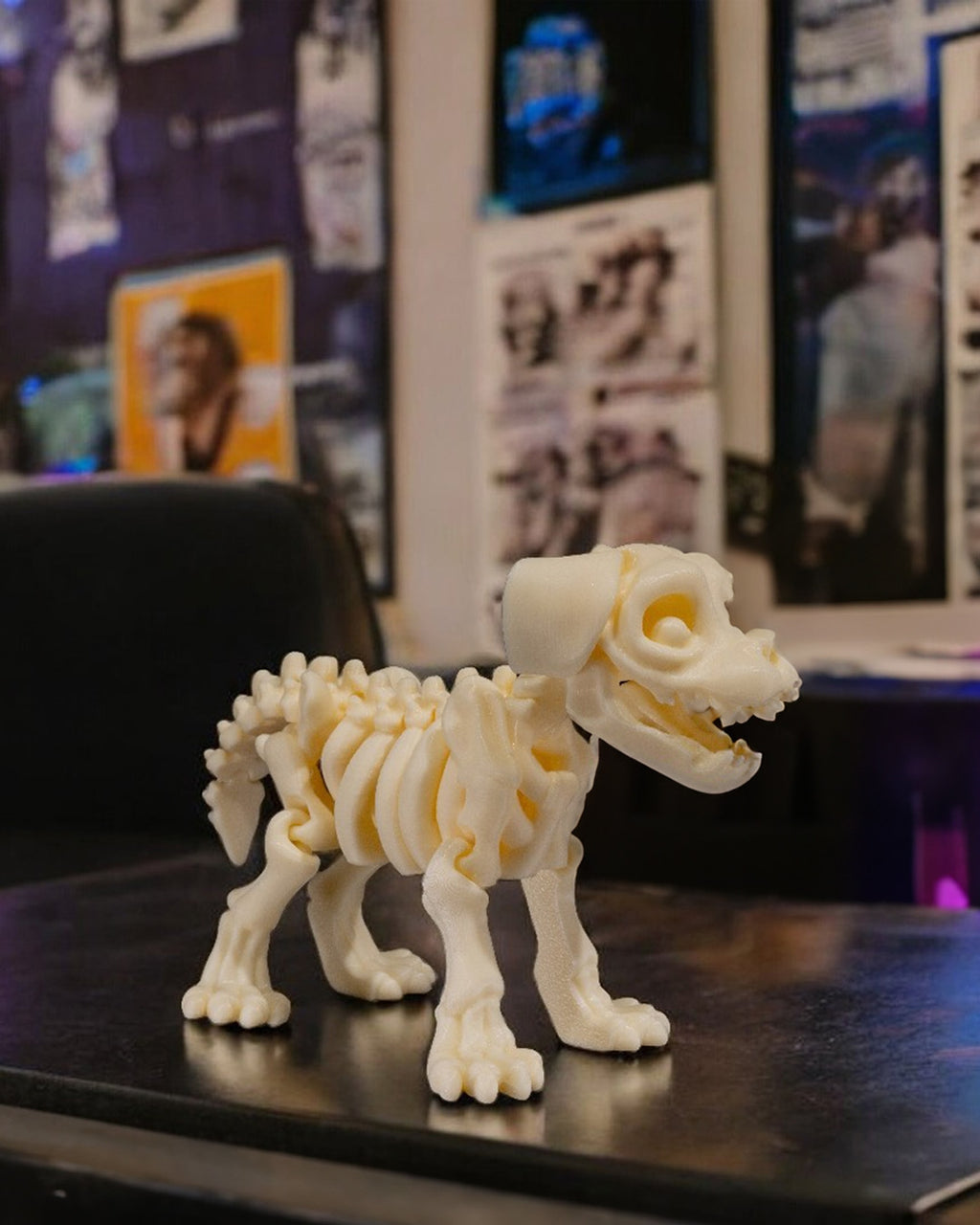 Skelett-Hund-Figur auf dunklem Schreibtisch mit unscharfem Gaming-Setup im Hintergrund, echter Größenvergleich im Raum