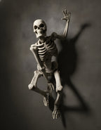 Skelett-Wanddeko 'The Skull' in gealterter Knochenoptik, Detailansicht von Schädel und Rippenbogen, direkt an dunkler Betonwand montiert mit dramatischem Spotlight und sichtbarem Schlagschatten auf der Wand