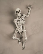Skelett-Wanddeko 'The Skull' in gealterter Knochenoptik, kletternde Pose an heller Wand montiert
