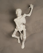Skelett-Wanddeko 'The Skull' in reinem Weiß, kletternde Pose an grauer Wand montiert