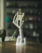 Skeletthand-Kerzenhalter mit brennendem Teelicht auf hellem Holztisch, Lifestyle-Ansicht