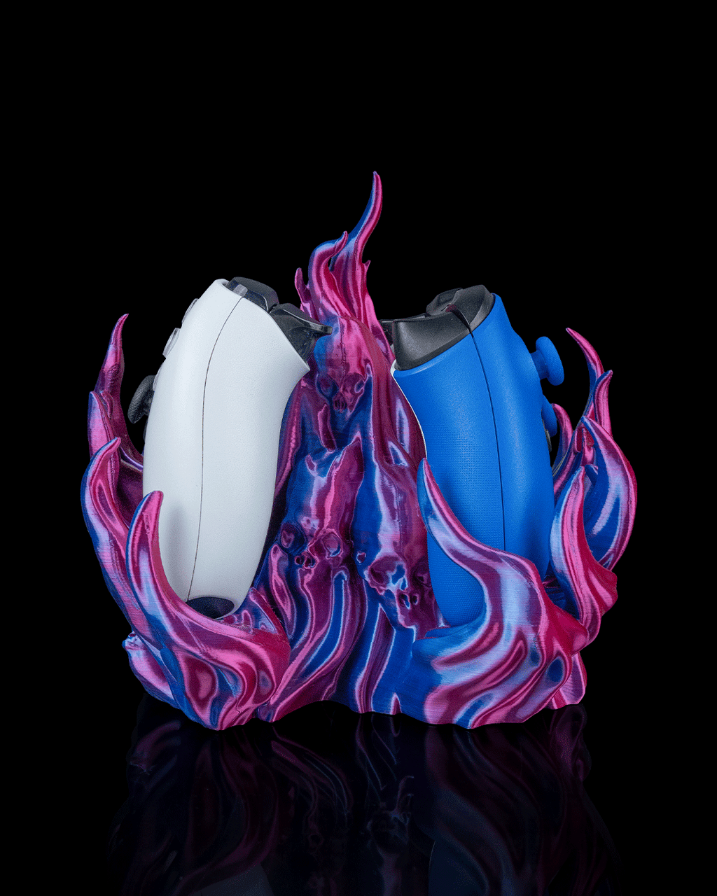 Skullflame Dual Controller-Halter in Pink-Blau-Lila, Seitenansicht freigestellt vor schwarzem Hintergrund, mit weißem Gaming-Controller links und blauem Gaming-Controller rechts, Totenkopf-Reliefs im Sockel sichtbar.