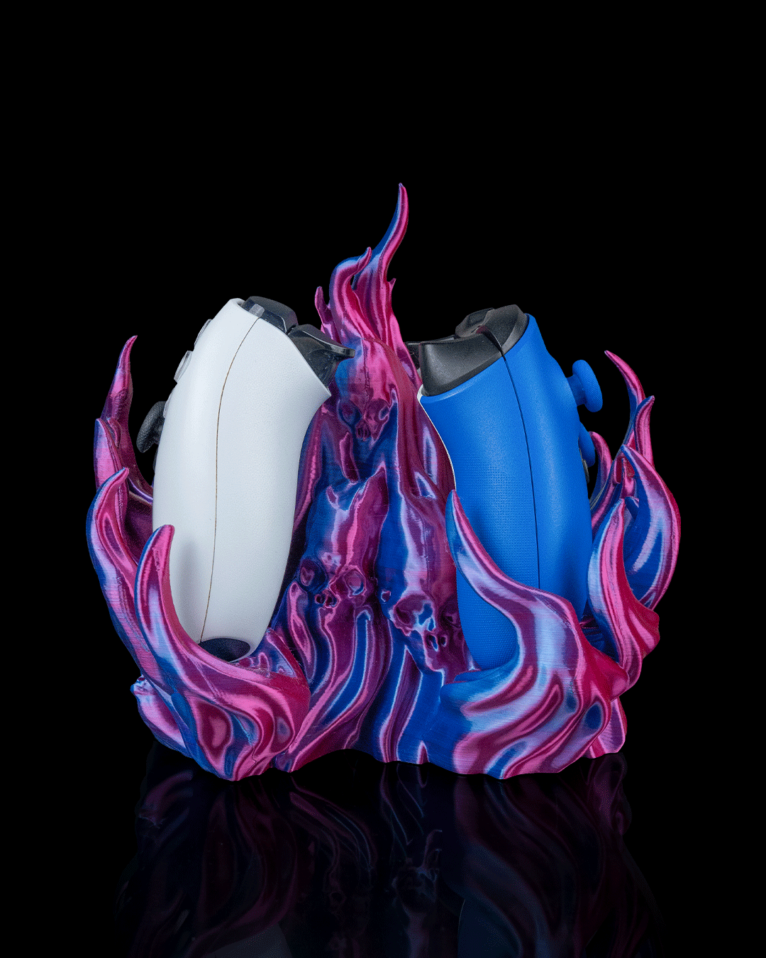 Skullflame Dual Controller-Halter in Pink-Blau-Lila, Seitenansicht freigestellt vor schwarzem Hintergrund, mit weißem Gaming-Controller links und blauem Gaming-Controller rechts, Totenkopf-Reliefs im Sockel sichtbar.