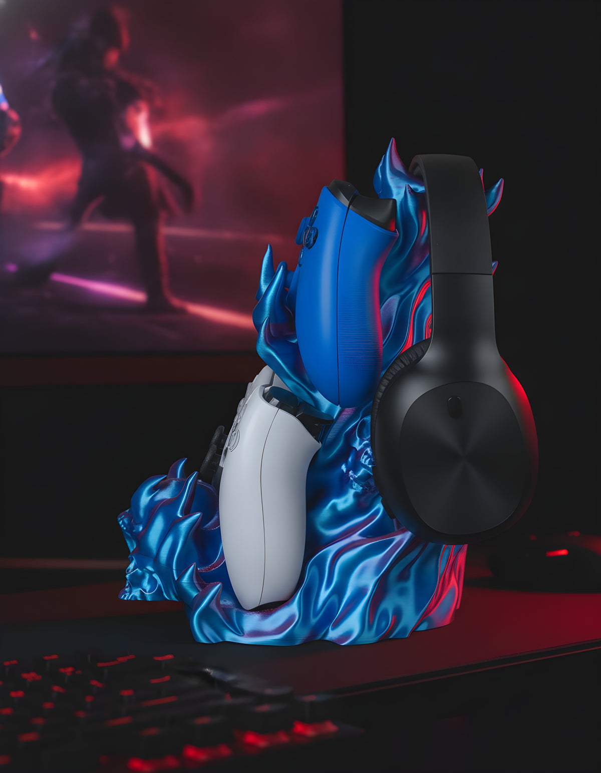 Skullflame Headset & Controller Ständer in Blau, Seitenansicht mit hängendem Over-Ear-Kopfhörer sowie blauem und weißem Gaming-Controller, auf dunklem Gaming-Schreibtisch mit rot-violettem RGB-Licht.