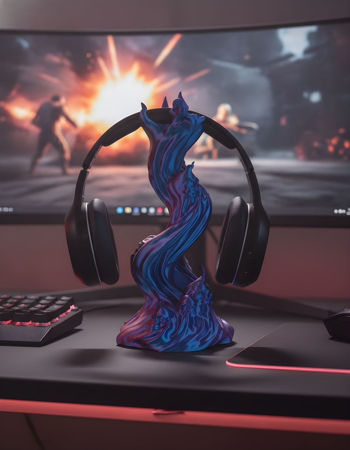 Skullflame Headset-Halter in Blau-Lila mit aufgehängtem Over-Ear-Kopfhörer, frontal auf dunklem Gaming-Schreibtisch, dahinter ein Gaming-Monitor mit unscharfer Explosionsszene, Tastatur und Mauspad mit rotem RGB-Licht im Vordergrund.