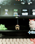 Kleine Spinnen-Figur steht auf einem Gaming-Schreibtisch vor einem Monitor, umgeben von weiteren Mini-Sammelfiguren.