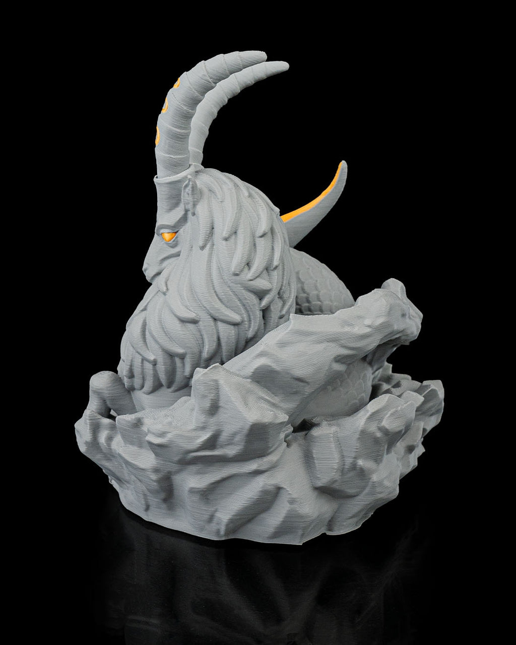 Steinbock-Skulptur in Grau aus schräger Perspektive mit Hörnern und Schwanzflosse, vor schwarzem Hintergrund