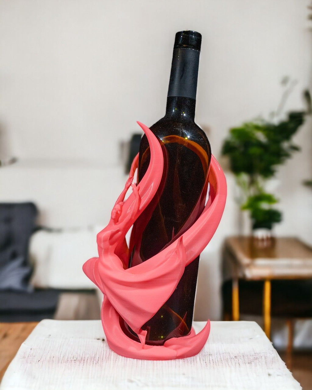 Tänzerin-Weinflaschenhalter in Pink auf weniger möblierter Fläche mit unscharfem Wohnzimmer-Hintergrund – Münch3D