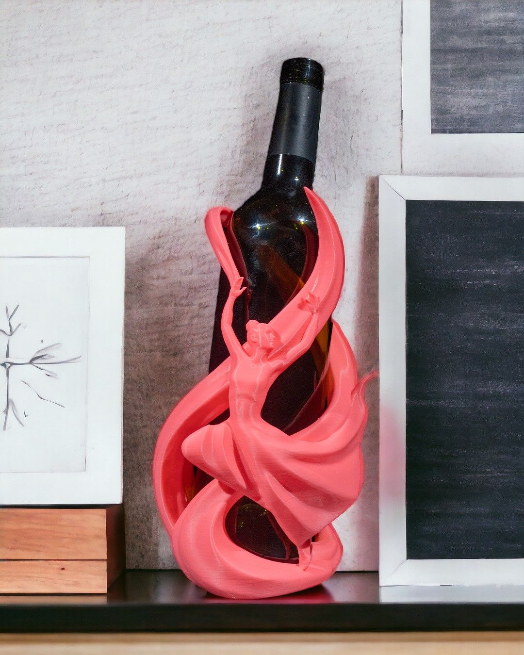 Tänzerin-Weinflaschenhalter in Pink auf Sideboard mit Bilderrahmen im Hintergrund, Frontalansicht mit Weinflasche – Münch3D
