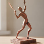 Tennisspieler-Statue in Kupfer-Bronze-Optik, Rückansicht schräg auf Holzoberfläche, weich unscharfer warmer Hintergrund – Münch3D