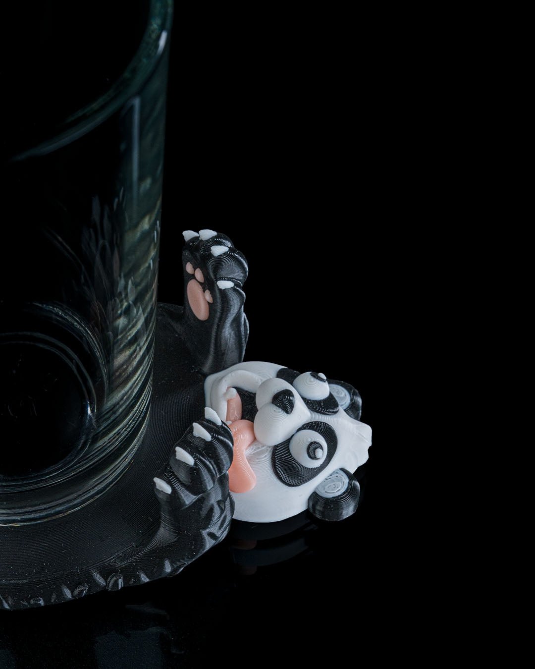 Lustiger Panda Untersetzer plattgedrückt mit Glas, Schrägansicht vor Schwarz – Münch3D