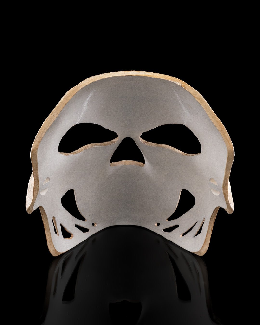 Innenansicht der Totenkopf-Halloween-Maske: Rückseite mit Aussparungen für Augen, Nase und Mund, vor schwarzem Hintergrund