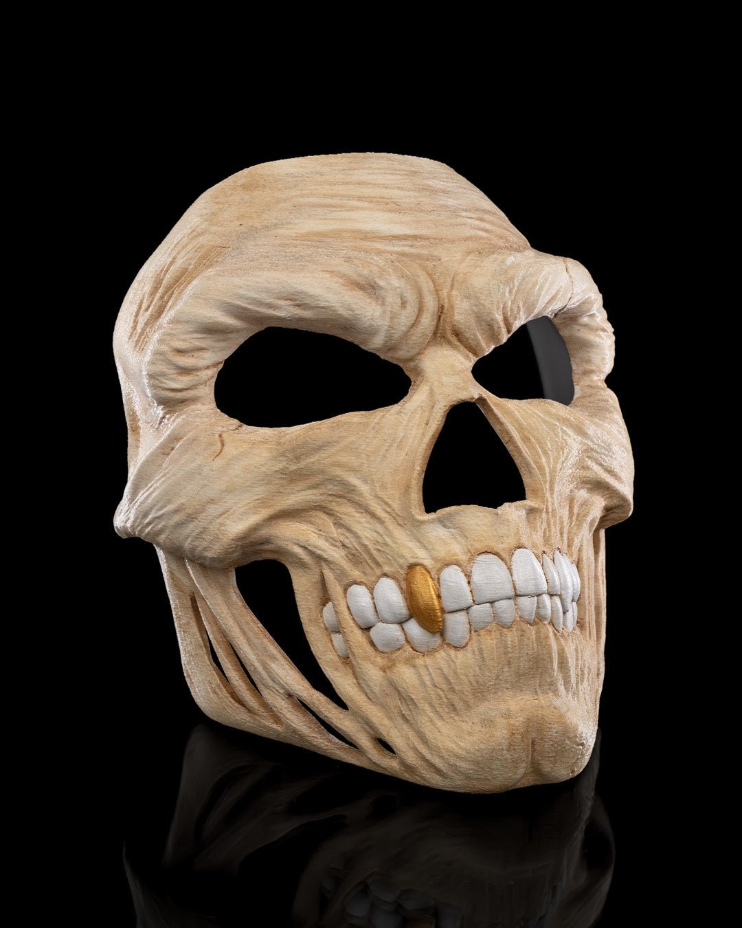 Totenkopf-Halloween-Maske in Creme mit goldenem Zahn-Akzent, leicht seitliche Ansicht vor schwarzem Hintergrund