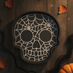 Totenkopf-Schale mit weißem Spinnennetz-Muster auf schwarzem Grund, Ansicht von oben auf dunklem Holztisch mit Herbstlaub und Mini-Kürbis