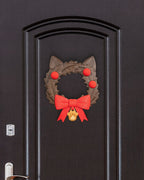 Weihnachtskranz in Katzenkopf-Form mit Katzenohren, roten Kugeln, roter Schleife und goldenem Pfotenanhänger, an dunkler Zimmertür mit Türgriff und Schloss montiert