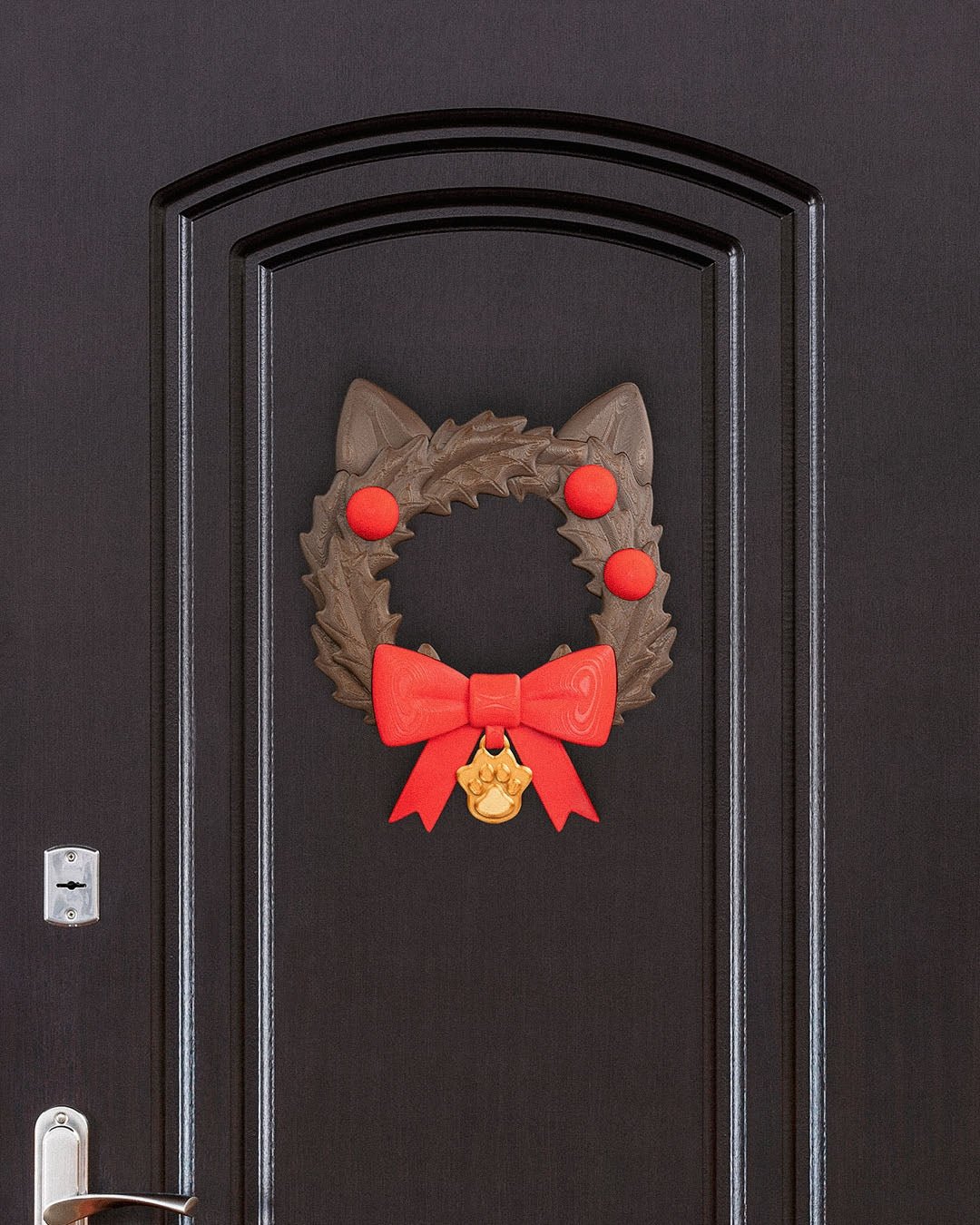 Weihnachtskranz in Katzenkopf-Form mit Katzenohren, roten Kugeln, roter Schleife und goldenem Pfotenanhänger, an dunkler Zimmertür mit Türgriff und Schloss montiert