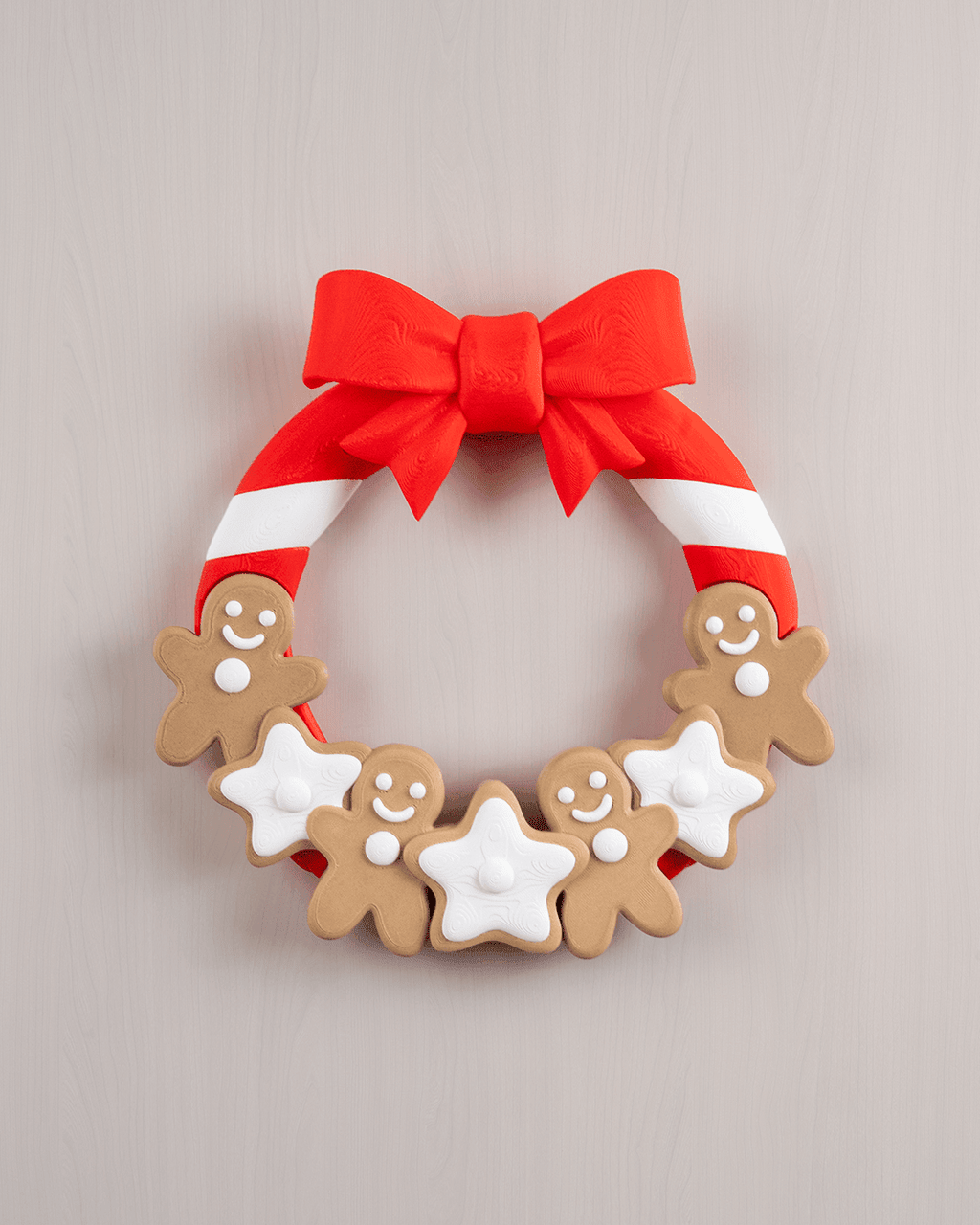 Weihnachtstürkranz mit Lebkuchenmännern, weißen Zuckerguss-Sternen und roter Zuckerstangen-Schleife, Frontalansicht an heller beige-rosa Wand