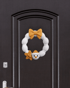 Weihnachtskranz aus weißer Strickoptik mit goldener Schleife und Schneemann-Applikation, an dunkler Zimmertür mit Türgriff und Schloss montiert
