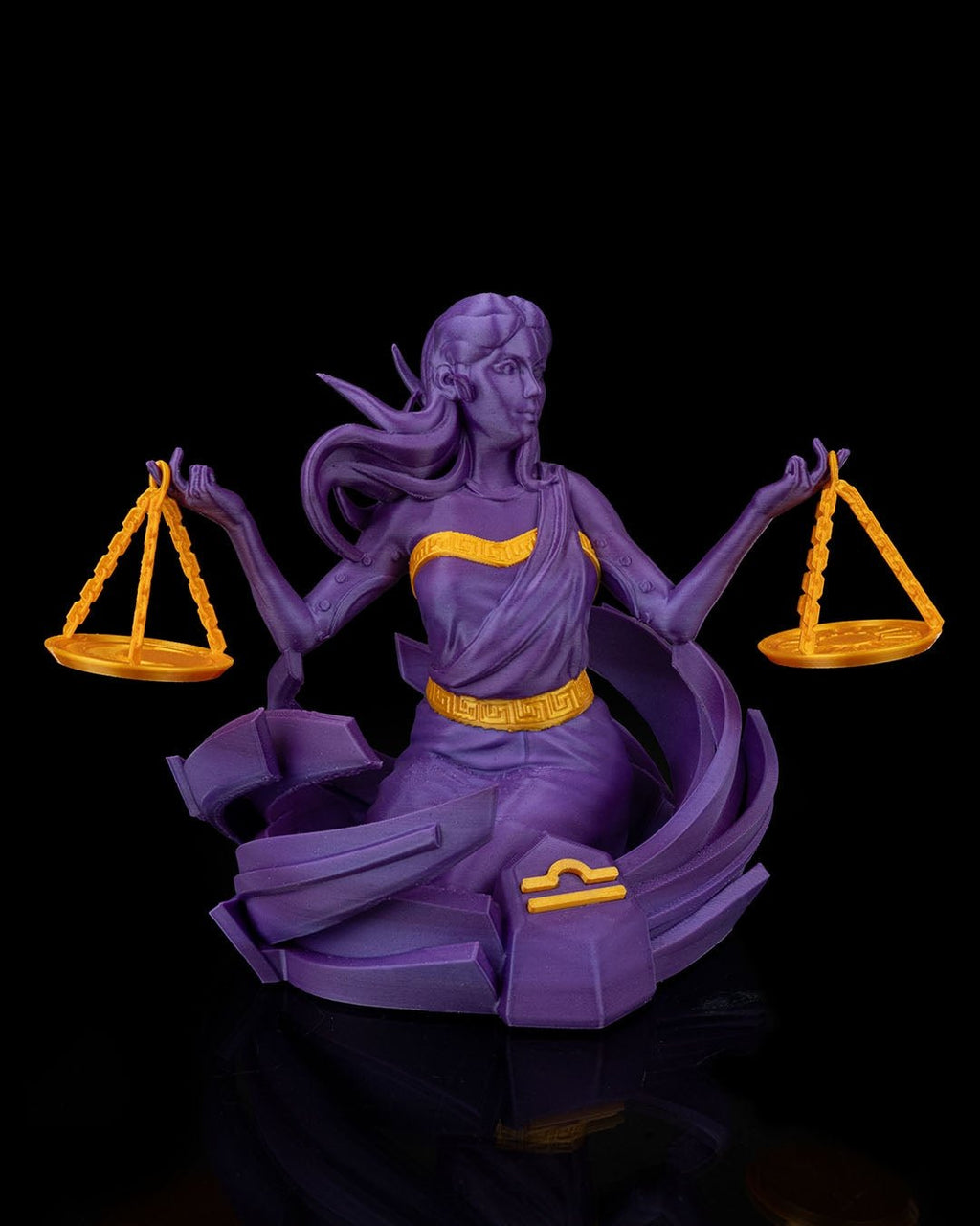 Waage-Göttin-Figur in Lila mit goldenen Akzenten, Frontalansicht mit beiden Waagschalen und Sternzeichen-Symbol am Sockel, vor schwarzem Hintergrund