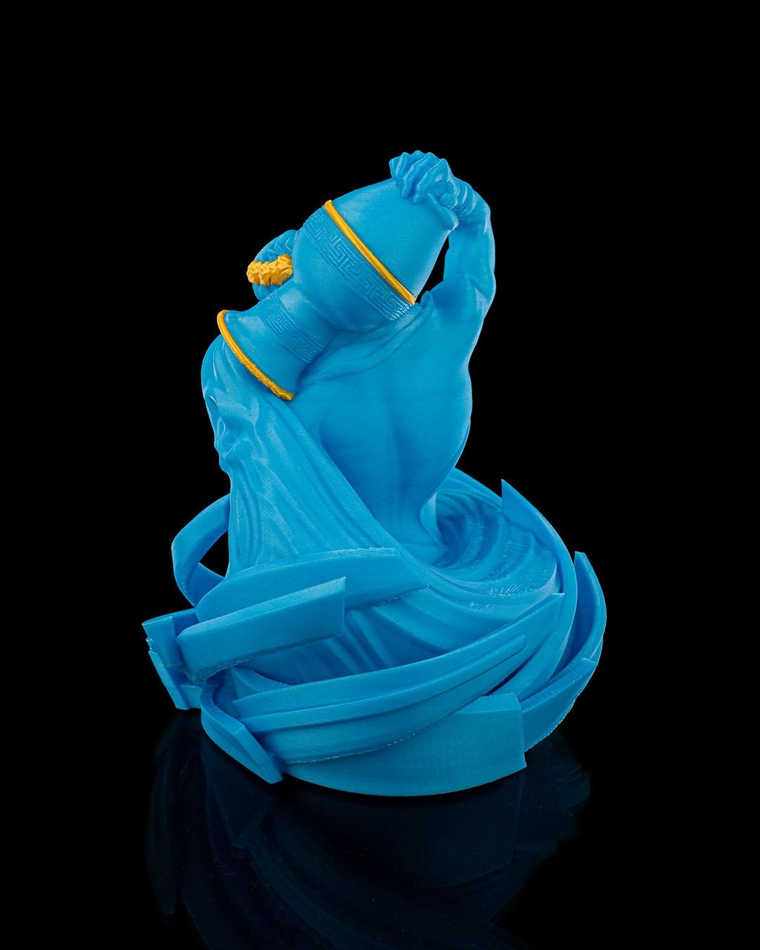 Wassermann-Figur in Blau aus schräger Perspektive mit Wasserdetails am Sockel, vor schwarzem Hintergrund